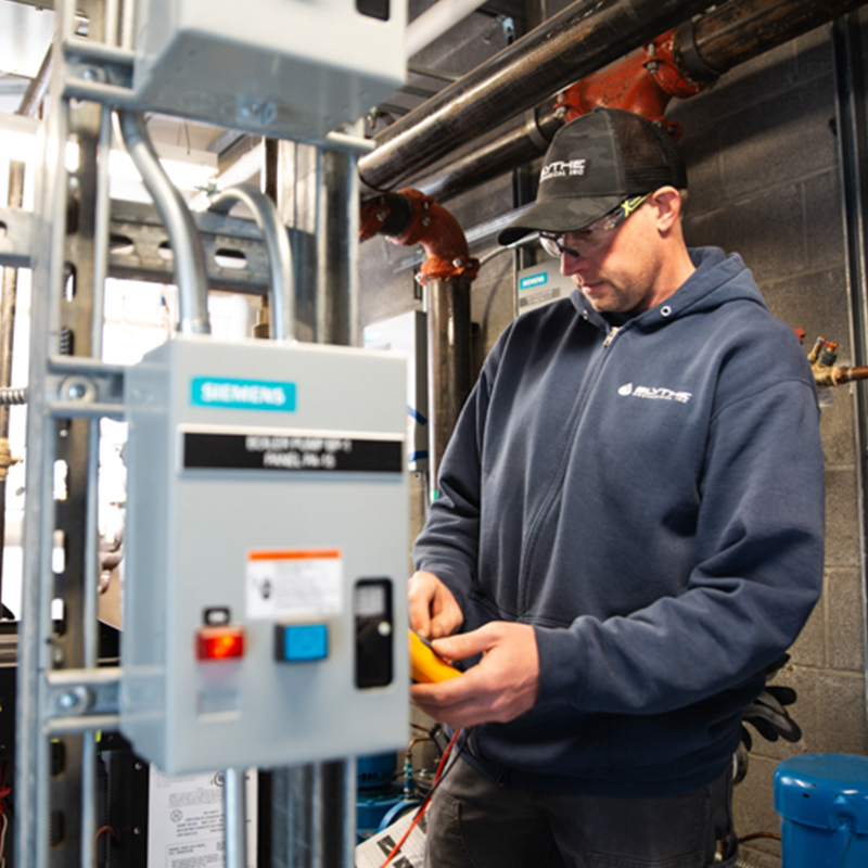 Technician performing preventative maintenance on commercial mechanical equipment to support system performance, efficiency, and reliability.