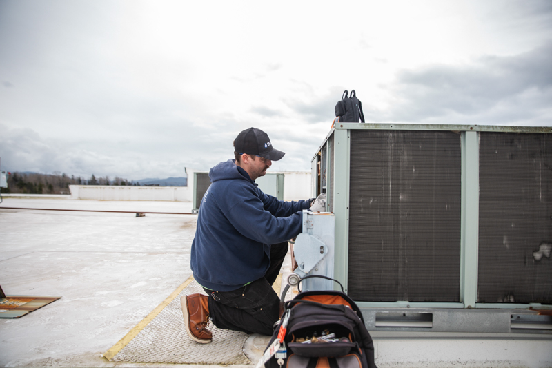 Technician performing preventative maintenance on commercial mechanical equipment to support system performance, efficiency, and reliability.